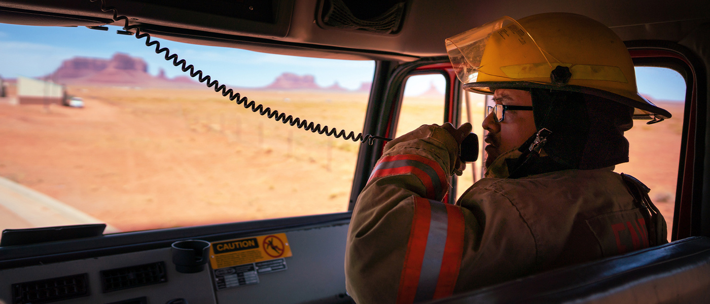 ES-BLOG-How to Integrate LMR and 5G -1400x600-image-1- first responder talking into a radio inside a truck