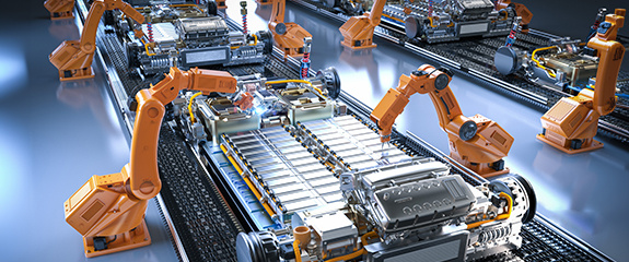 The image shows an automated manufacturing line for what appears to be electric vehicle battery packs or modules. Multiple orange industrial robotic arms are positioned along an assembly line, working on rectangular battery assemblies. The battery units can be seen on conveyor systems, with their metallic cells visible in organized arrays. The production environment has a blue-tinted, high-tech industrial appearance typical of modern automated manufacturing facilities. This likely represents an EV battery production facility using robotic automation for precision assembly and handling.0