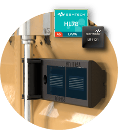 Close-up image of a black electronic device mounted on a light wooden or beige surface. The device appears to be a network or IoT gateway with ventilation slots on its casing. In the upper portion of the image, there's a teal Semtech product label showing 'HL79' which likely indicates a cellular IoT module or component. The device seems to be part of a smart home or industrial IoT setup, demonstrating practical application of Semtech's connectivity technology.